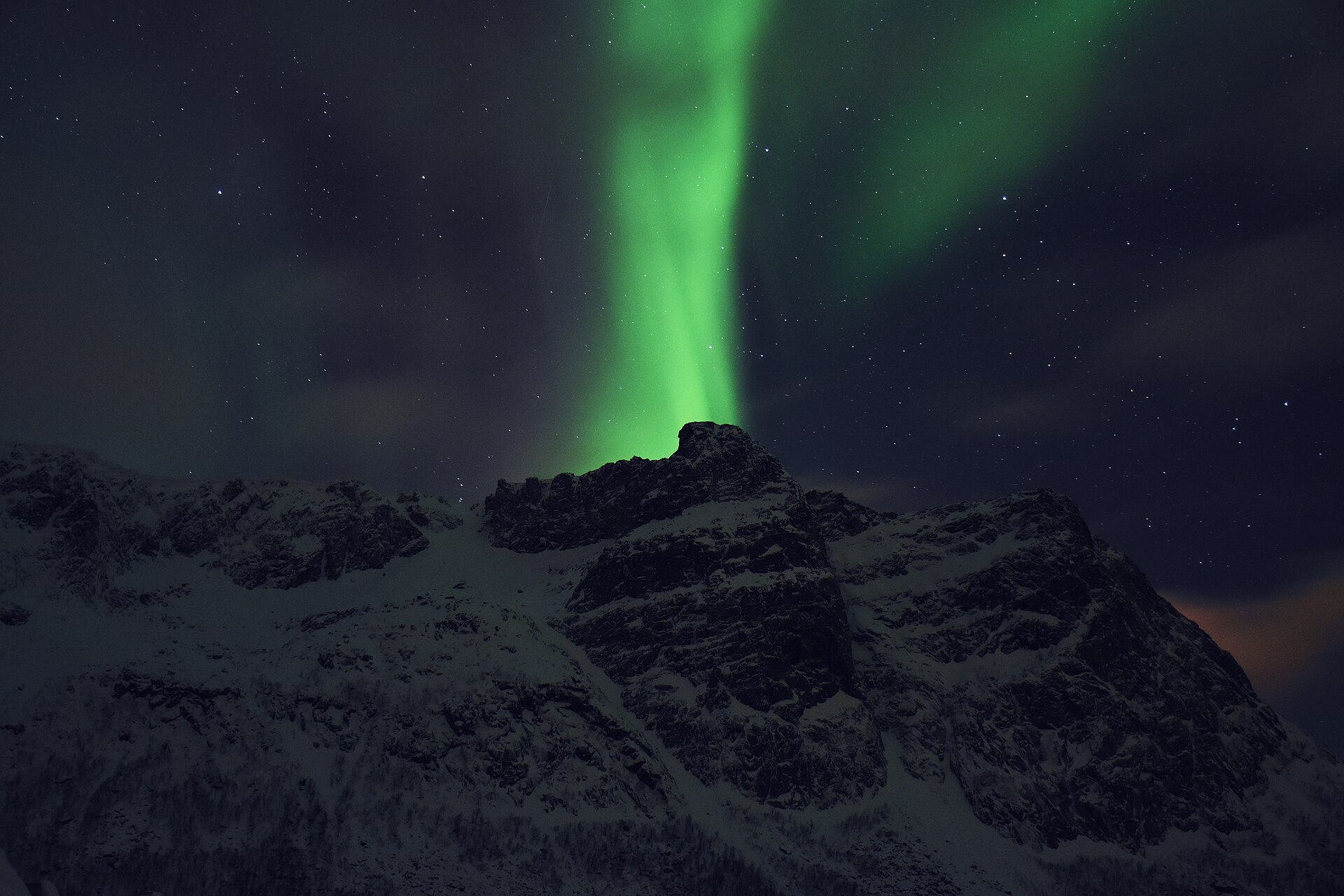 Northern lights over snow-covered mountains near Tromsø