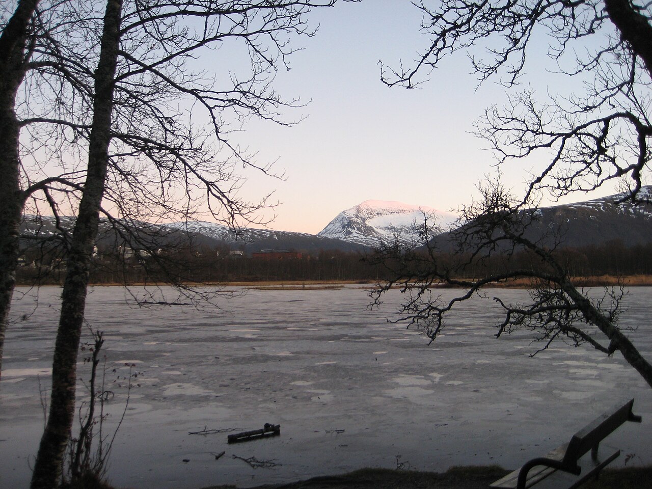 Frozen Prestvannet lake framed by bare trees and mountains