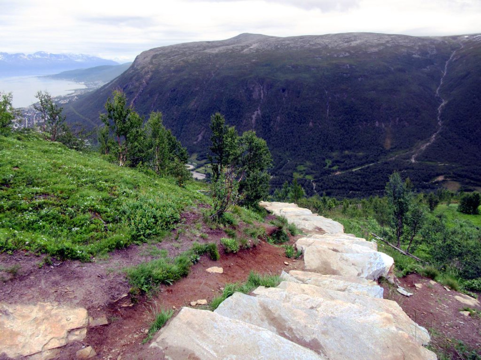 Stone steps of Sherpatrappa leading down a green hillside toward Tromsø