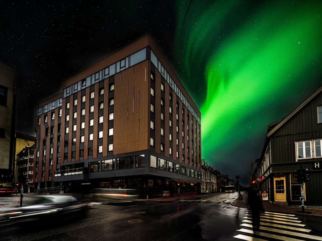 City hotel building beneath green northern lights at night