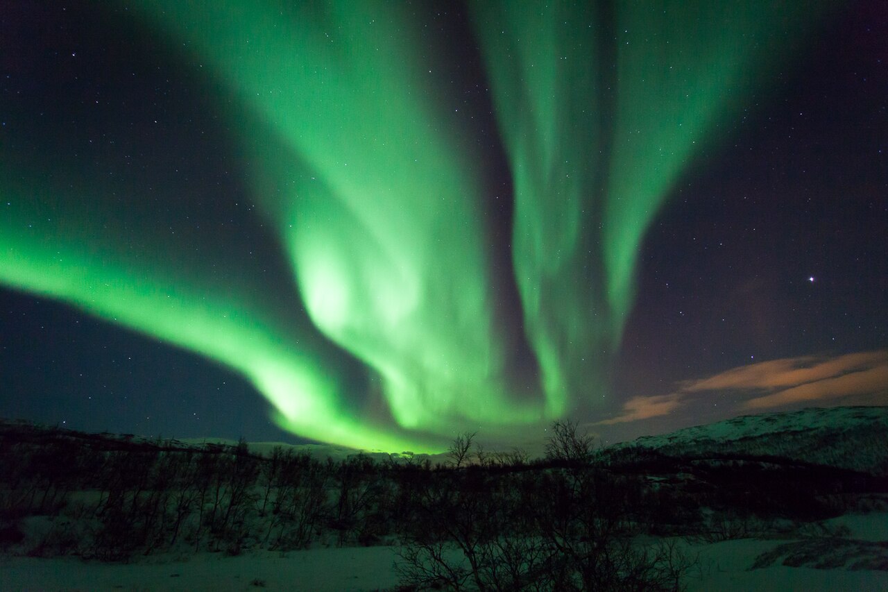 Northern lights over snowy hills on Ringvassøya near Tromsø