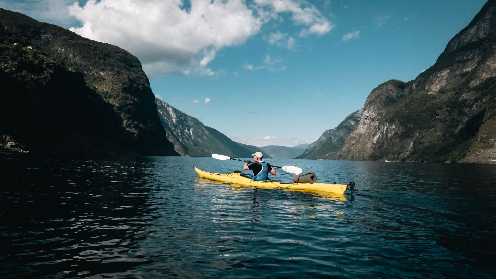 Yellow kayak crossing a dramatic Norwegian fjord