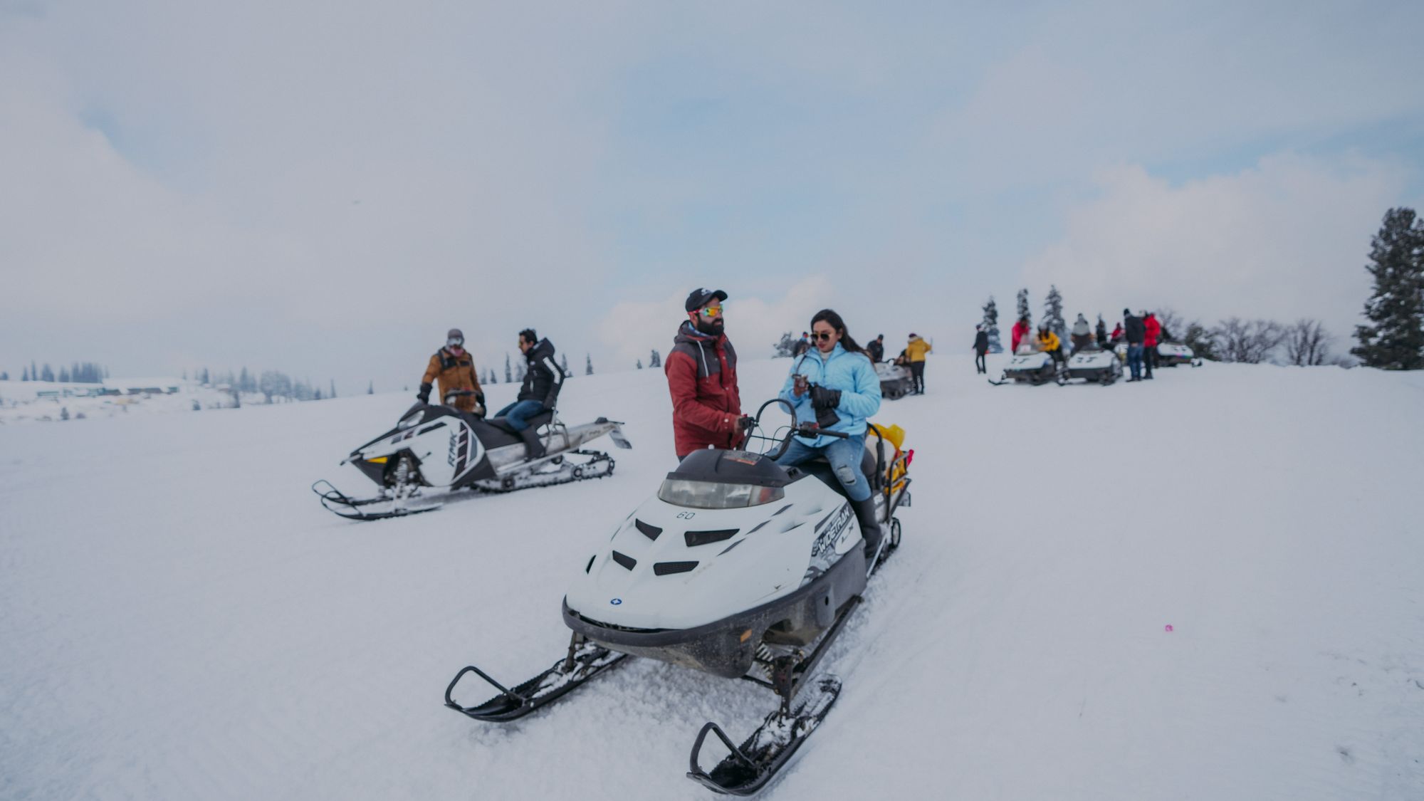 Group preparing to ride snowmobiles across a snowy landscape
