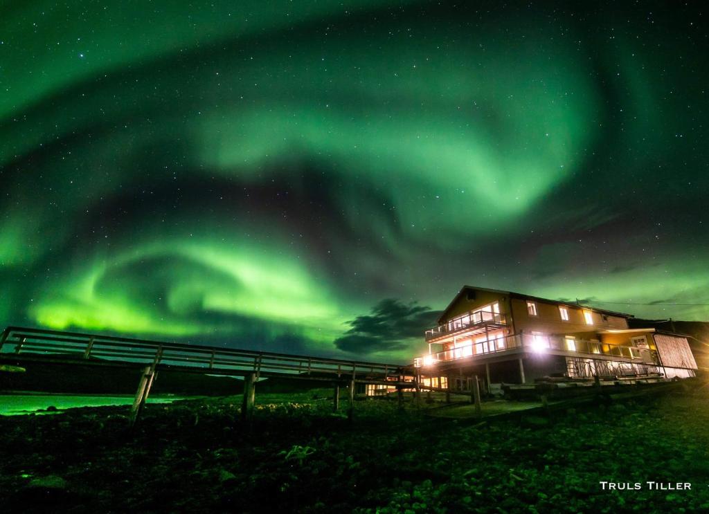 a house under the northern lights in the sky at Buvik Sea Lodge Apartments in Buvik — Buvik Sea Lodge Apartments