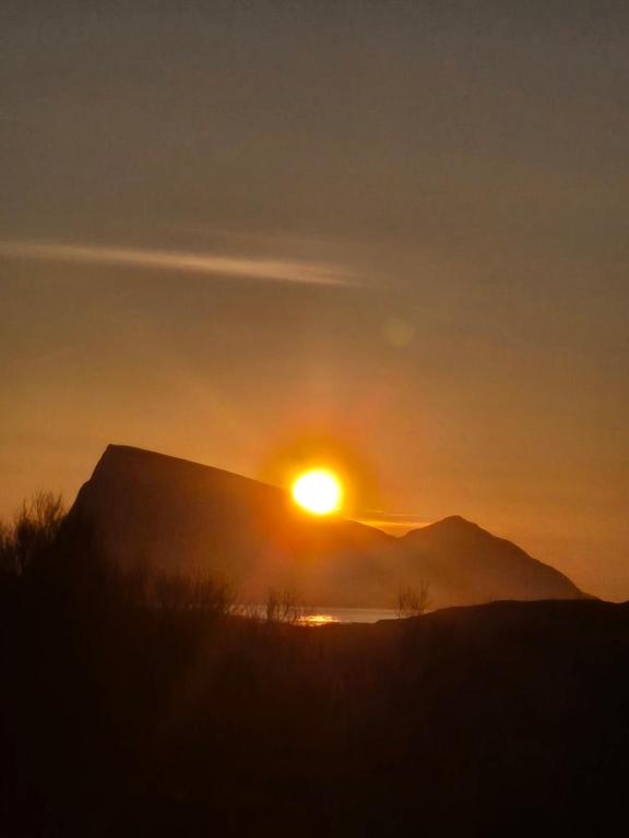 a sunset over a mountain with the sun setting at Cabin Aurora Borealis in Sommarøy — Cabin Aurora Borealis