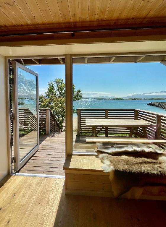 a house with a view of the ocean from a deck at Ecolodge Båthuset 69Nord in Sommarøy — Ecolodge Båthuset 69Nord