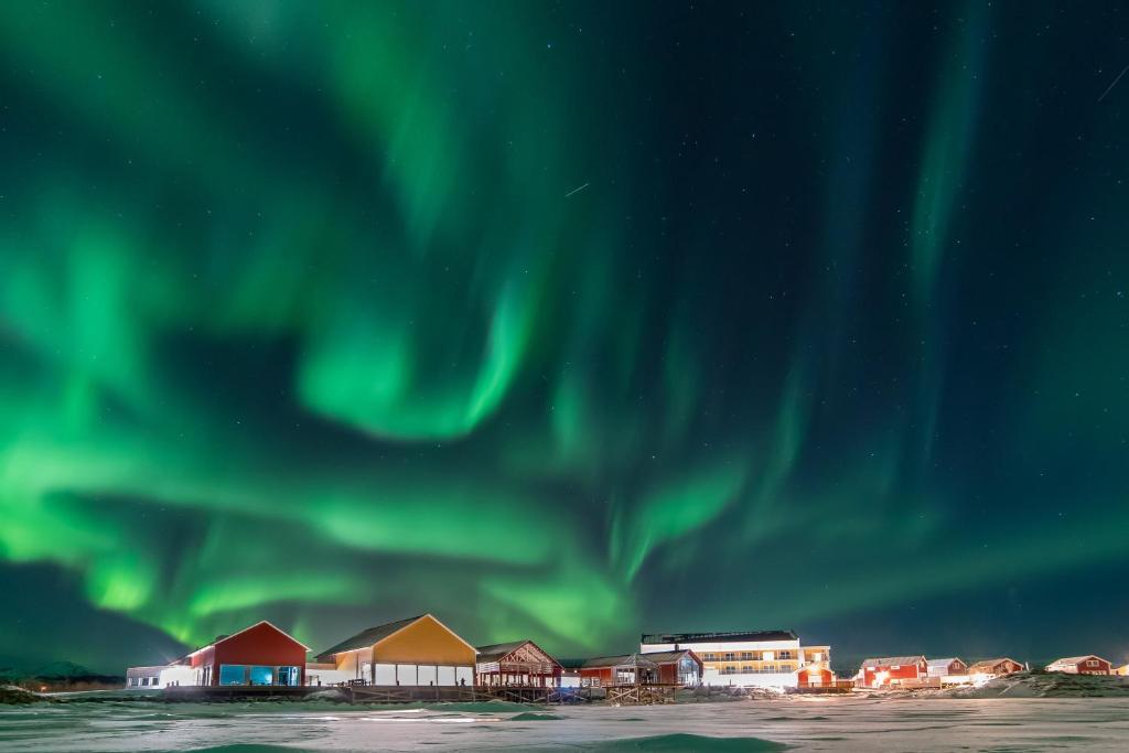 a group of buildings under the aurora borealis at Sommarøy Arctic Hotel Tromsø in Sommarøy — Sommarøy Arctic Hotel Tromsø