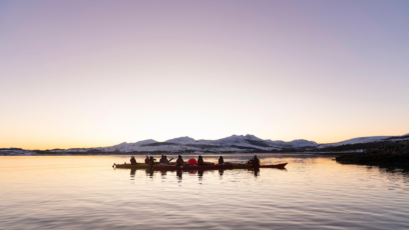 Guided winter sea kayakers paddling along the Arctic coast