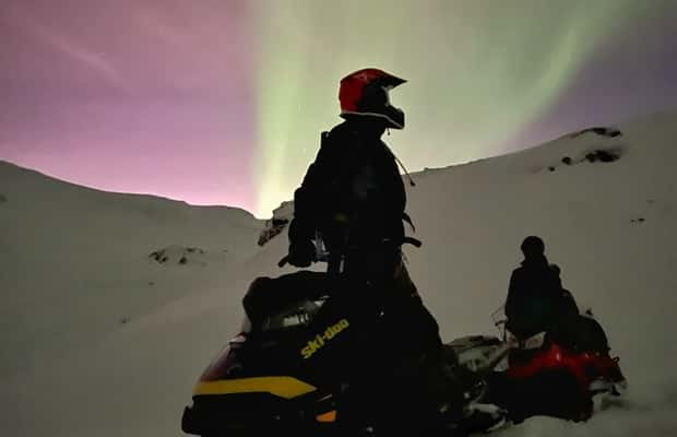 Snowmobiles riding through an Arctic valley at blue hour — photo 1 of 5